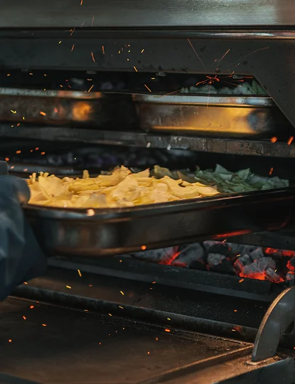 Honest Greens chef cooking over open fire in the Josper oven, showcasing our craft of cooking.